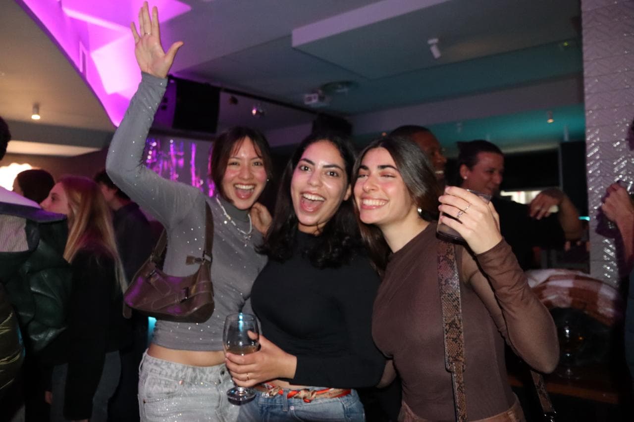 Three guests smiling together on the dance floor at a Barcelona International Social event